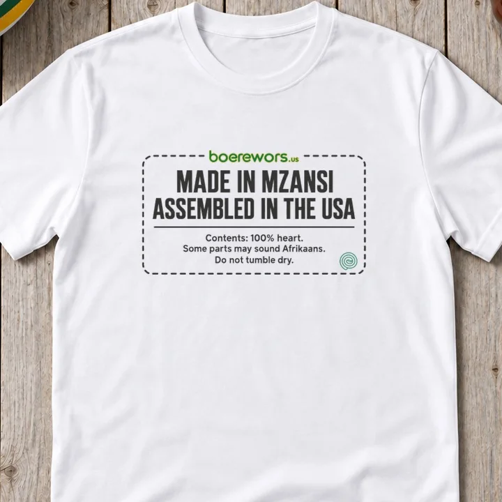 White tee printed with clothing-label design: Made in Mzansi, Assembled in the USA. Contents: 100% heart.