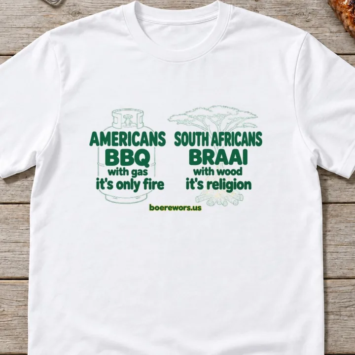White tee printed with two columns: Americans BBQ with gas, it's only fire. South Africans braai with wood, it's religion.